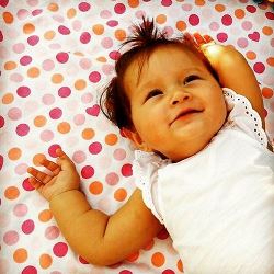 Девочка лежит на пелёнке от Swaddle Designs